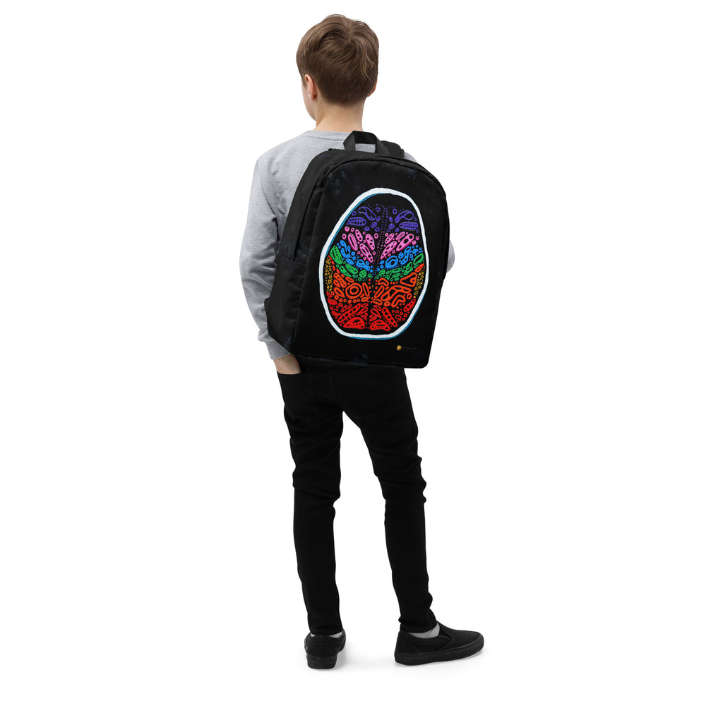 Lifestyle shot, right-front angle on model wearing the Penumbra backpack. Bold all-over abstract design with centered wordmark; padded shoulder straps shown for comfortable everyday commuting and urban streetwear style. Nicholas Hayes Artist.