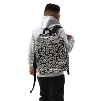 Lifestyle shot, right-front angle on model wearing the Penumbra backpack. The backpack displays a bold all-over abstract design; padded shoulder straps for comfortable everyday commuting and travel in the USA.  Nicholas Hayes Art.