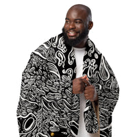 Lifestyle scale image of a black make with the Penumbra No. 1 sherpa blanket wrapped around him and held up vertically. The blanket is a full abstract design with a black backdrop and white shapes floating creating a three dimensional look. Lightweight, warm polyester sherpa ideal for living rooms, bedrooms, or studios. Art by Nicholas Hayes.