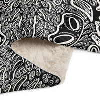 Close-up corner of the Penumbra No. 1 sherpa blanket showing plush beige sherpa underside, soft printed face, and neat stitching. Emphasizing warmth, softness, and durable construction.  The artwork has a black background and three dimensional white shapes popping off the blanket.  Art and design by Nicholas Hayes.