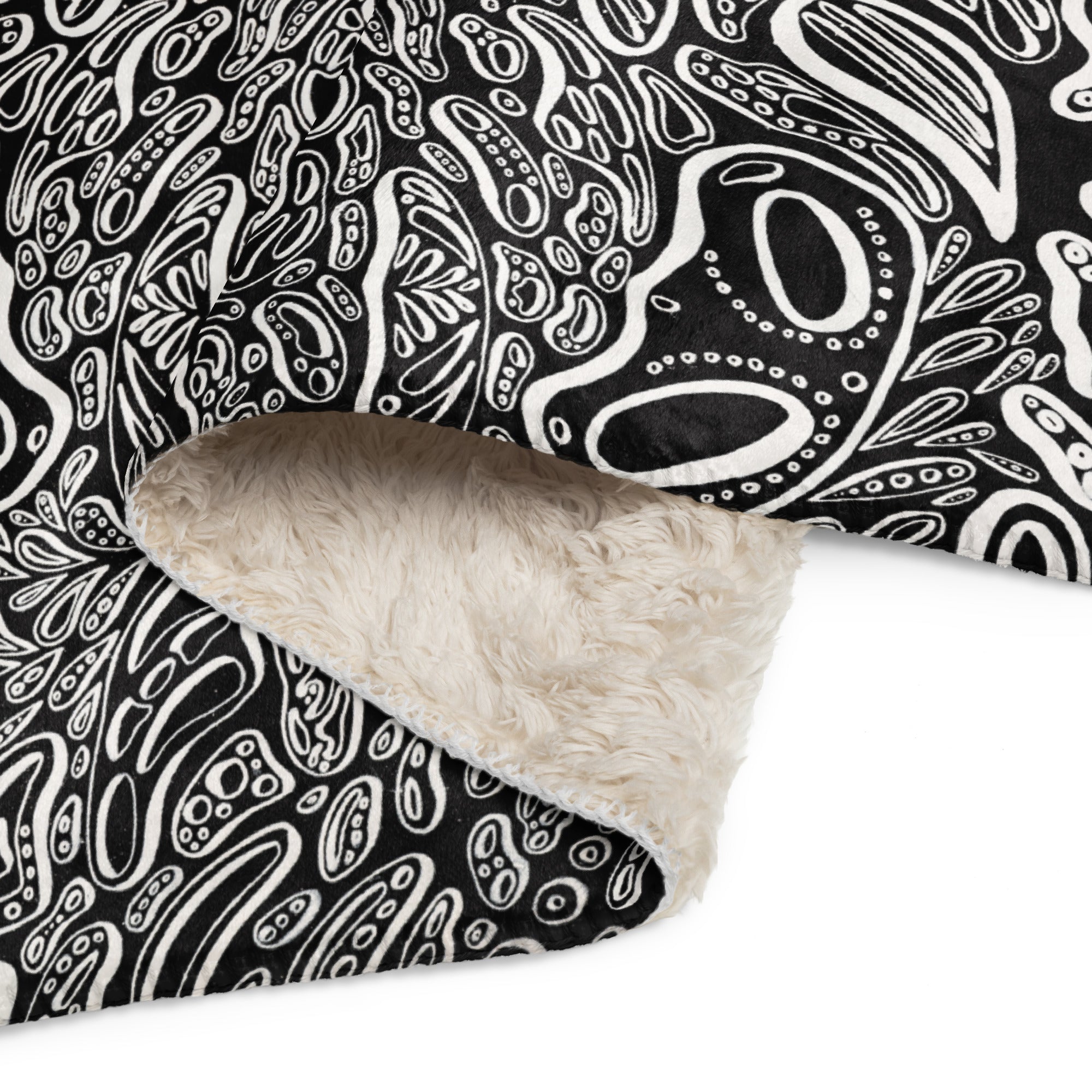 Close-up corner of the Penumbra No. 1 sherpa blanket showing plush beige sherpa underside, soft printed face, and neat stitching. Emphasizing warmth, softness, and durable construction.  The artwork has a black background and three dimensional white shapes popping off the blanket.  Art and design by Nicholas Hayes.