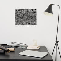 A fine art print featuring a black and white abstract pattern, displayed on a wall above a desk with a lamp and various office supplies. Fine art print by Chicago artist Nicholas Hayes. Black-and-white abstract design, shown framed above a desk to illustrate scale and modern home office décor.