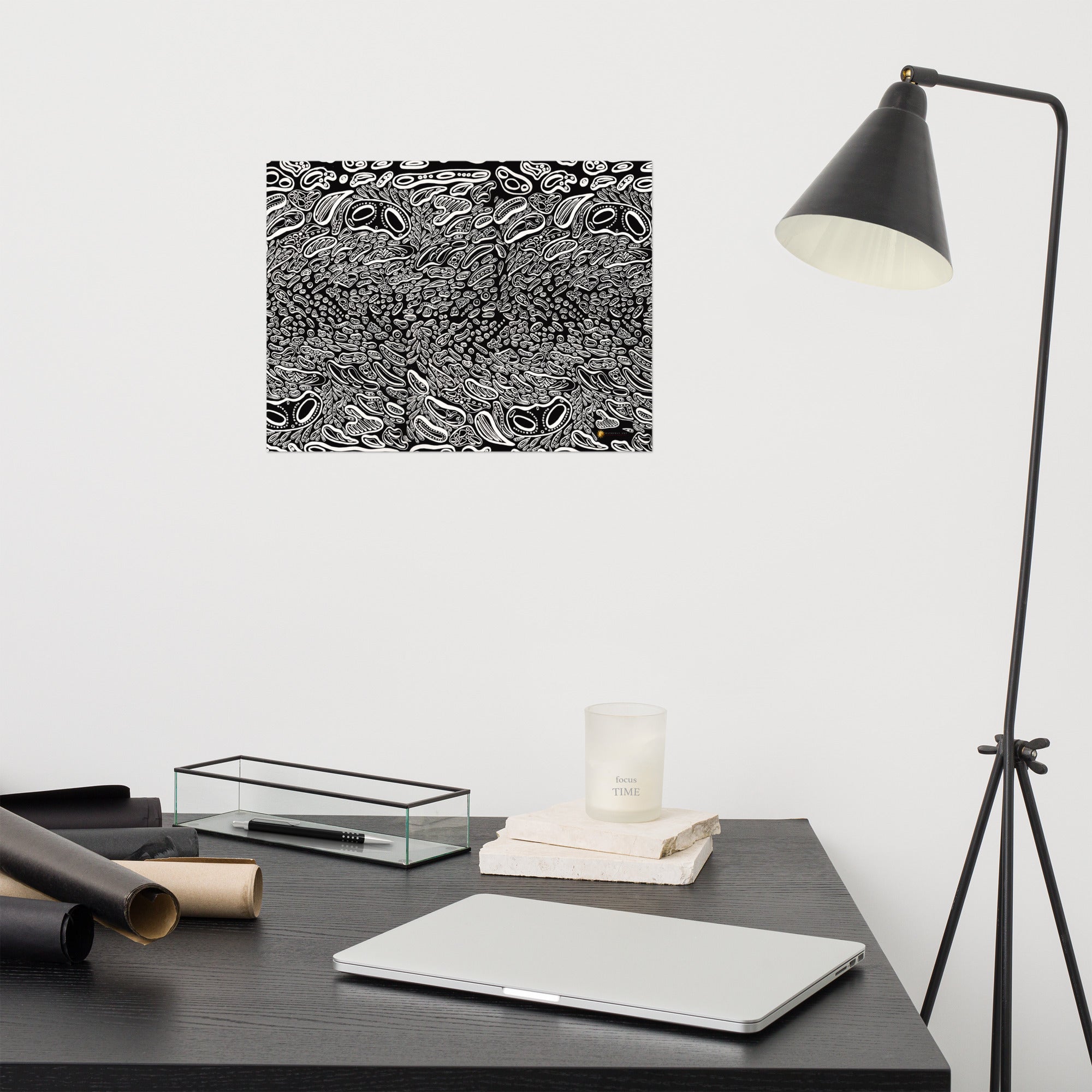 A fine art print featuring a black and white abstract pattern, displayed on a wall above a desk with a lamp and various office supplies. Fine art print by Chicago artist Nicholas Hayes. Black-and-white abstract design, shown framed above a desk to illustrate scale and modern home office décor.