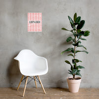 A Nicholas Hayes fine art print with a red and white geometric pattern and the word 'Refused' displayed on a wall, accompanied by a potted plant and a modern white chair with wooden legs. Bold black REFUSED wordmark over repeating red pattern, 12x16 museum-quality matte paper focal point for modern interiors.