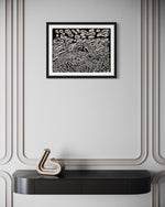 A framed abstract painting hanging on a wall above a decorative console table, with black and white colors predominating. Front view of ‘Penumbra Painting No. 1’ by Nicholas Hayes. Original 18×24 acrylic on heavyweight canvas paper, professionally framed, one-of-a-kind artwork ready to hang; contemporary statement piece for modern home or gallery walls.